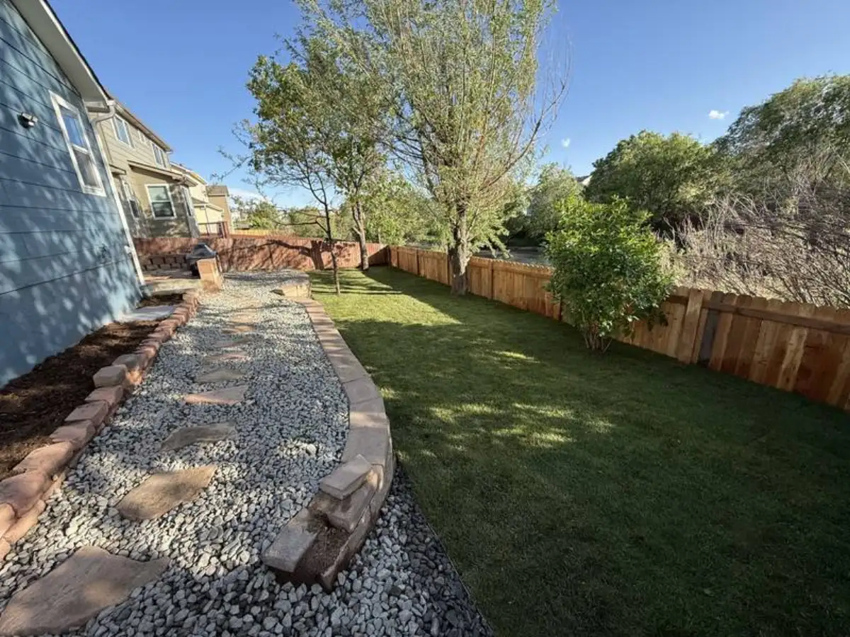 Backyard landscaping with rock borders and sod lawn in Colorado Springs