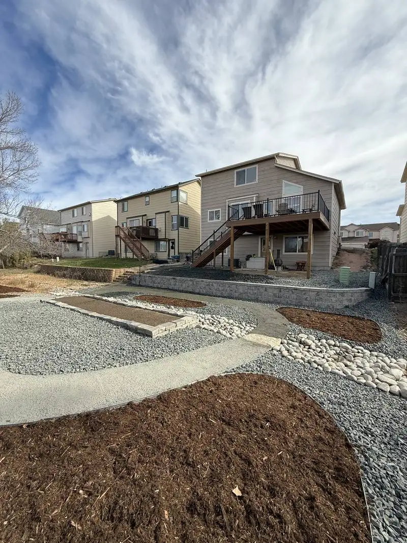 Custom fire pit area with gravel and retaining wall in Colorado Springs backyard