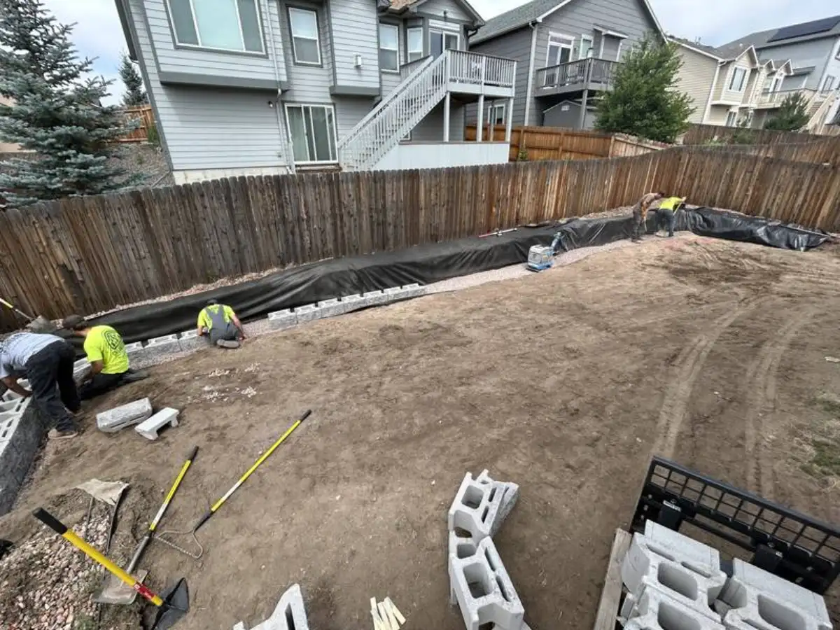Crew installing segmental block retaining wall with fabric in Colorado Springs