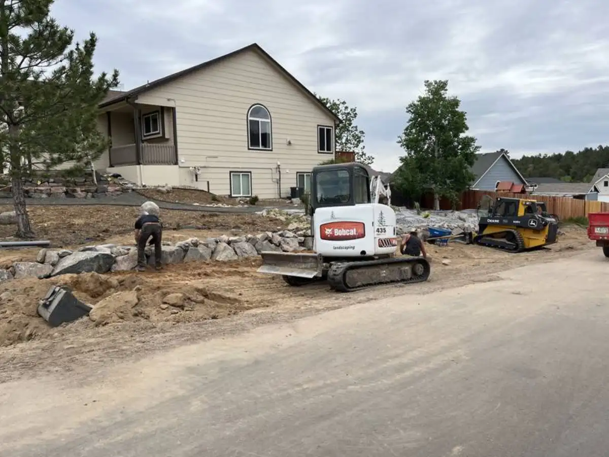 Excavator placing boulders for retaining wall construction in Colorado Springs