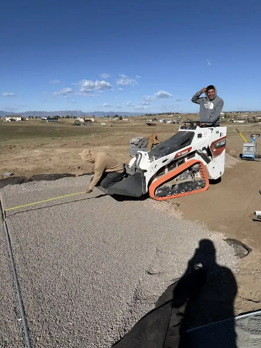Two crew members preparing and measuring a compacted aggregate base
